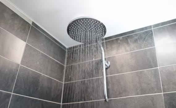 In bathroom, water flows from shower tap. Harm and benefits of cold shower in morning