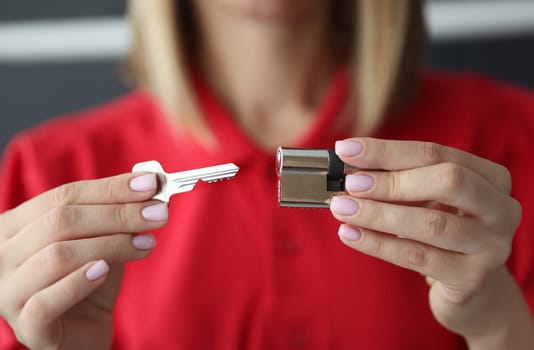 Female hands hold key and lock. Lock opening and replacement services concept