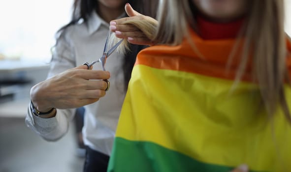 Woman cuts split ends of hair of her friend with lgbt flag. Beauty salons for sexual minorities concept