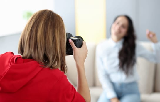 Woman photographer photographs model on couch. How to make money on photos concept