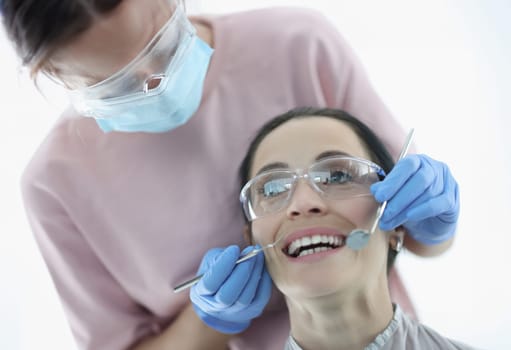 Woman demonstrates her teeth at dentist appointment. Dental services and treatment concept