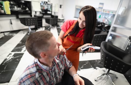 Woman hairdresser serves man in beauty salon. Men's hairstyle training concept