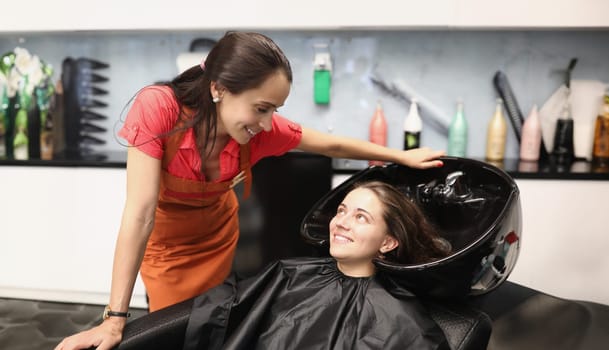 Hairdresser tells client how to properly wash her hair. Hair and scalp care concept