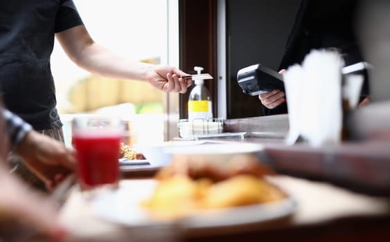 Man's hand holds out contactless bank card to cashier to pay for lunch. Payments by term in public places