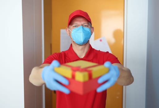 Courier wearing medical protective mask brought box with protective gloves. Delivery of parcels to coronavirus pandemic concept