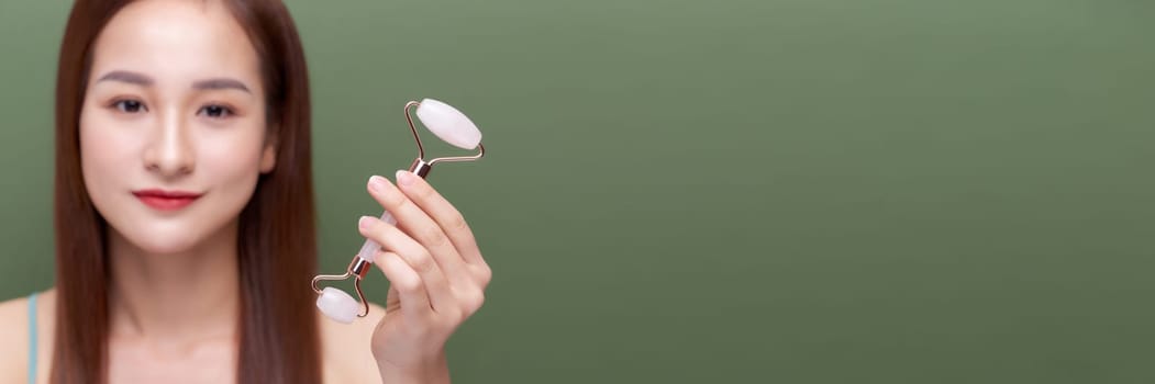 Panorama of girl uses beauty gua sha jade quartz roller. 