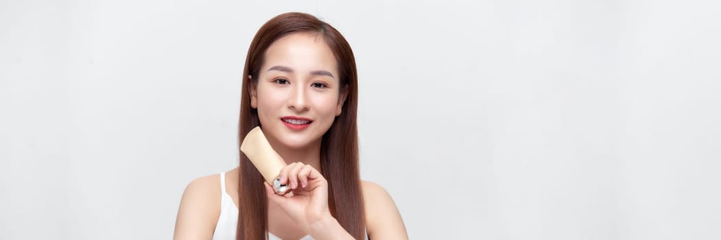 Beautiful asian woman face portrait holding and presenting cream tube product on banner.