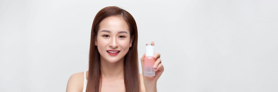 Smiling young beauty asian woman showing skincare products isolated on banner background.