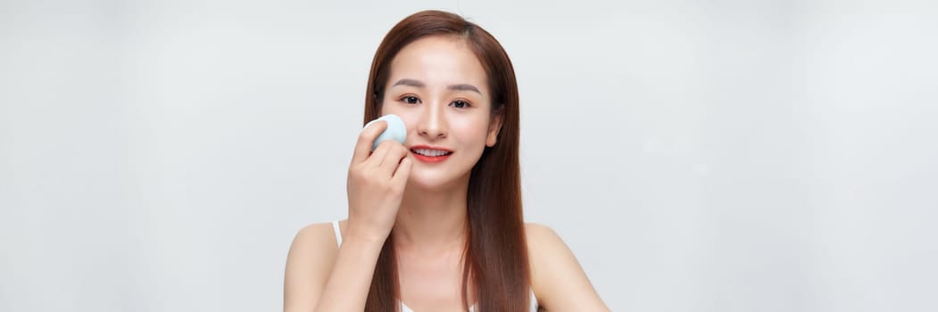 Asian woman using sponge blender make up tool on face on banner background