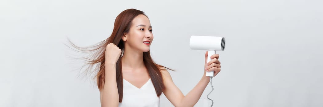 Banner of beautiful smiling girl with long straight hair using hairdryer. 