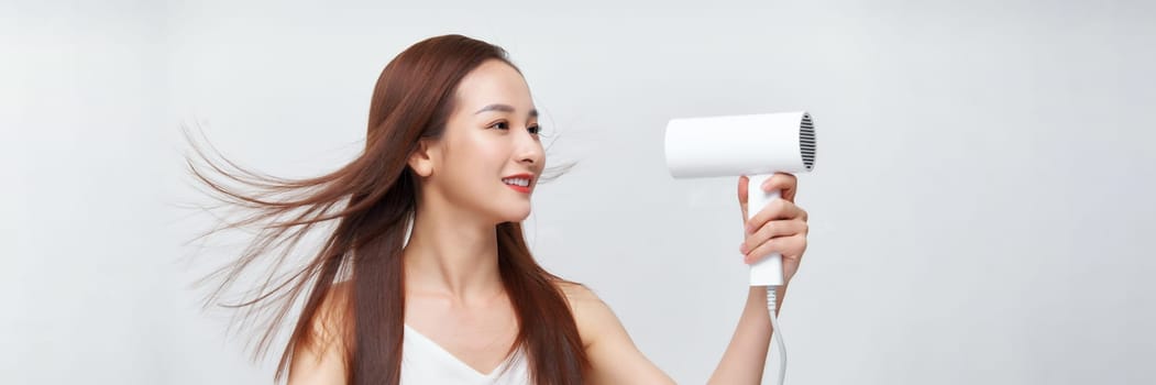 portrait of a young woman using a dryer on white banner background