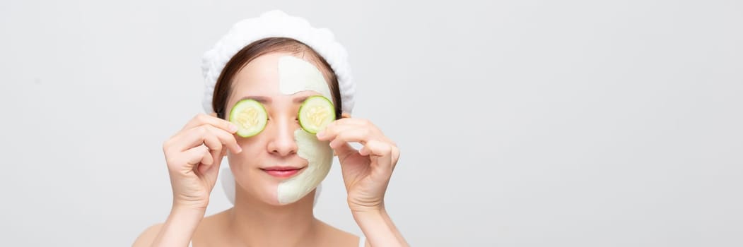 Beautiful girl holding a slice of cucumber in front of her face. 