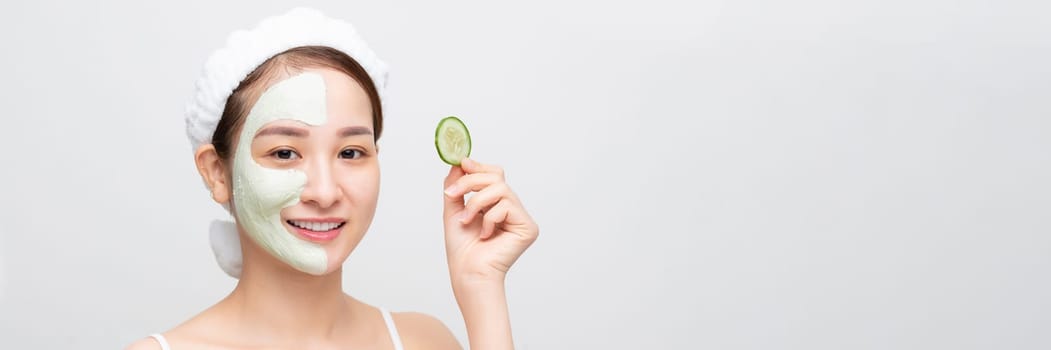 Young asian beautiful woman holding fresh cucumbers, white mask cosmetic on face, banner wide