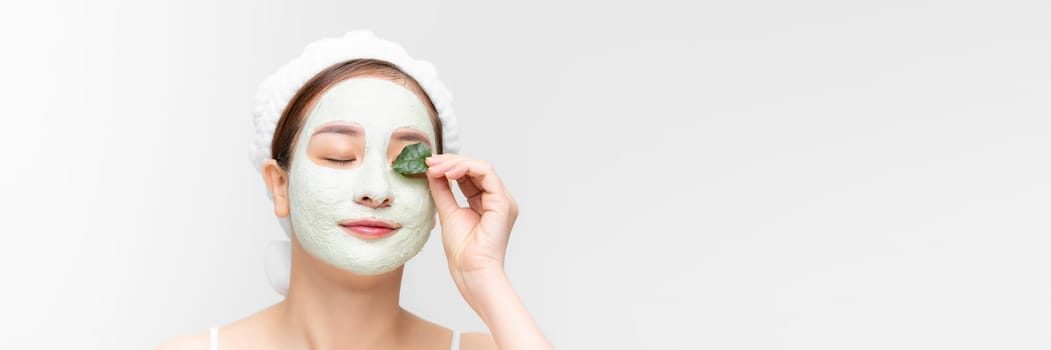 Minimal beauty portrait woman applying white nourishing mask or creme on face, green leaf in hand. banner