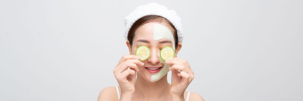 naked young woman with clay mask and cucumbers on face isolated on wide banner