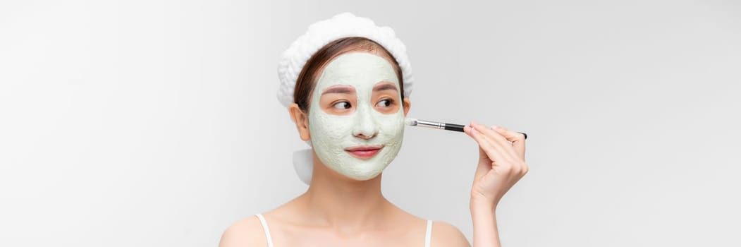 A woman with a green clay cosmetic mask on a white background. Banner wide