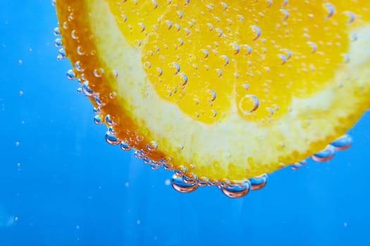 Image of Edge of orange slice covered in silvery bubbles with blue background