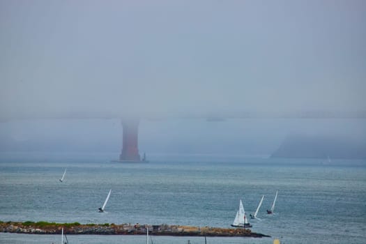 Image of Boats with sails out on San Francisco Bay with foggy and obscured Golden Gate Bridge