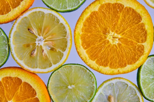 Image of Slices of citrus fruits with lemons and limes with larger orange slices on white background