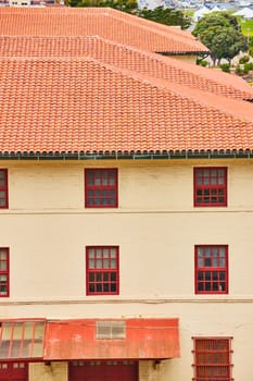 Image of Cream colored building with red trim around windows and orange clay shingle roofs