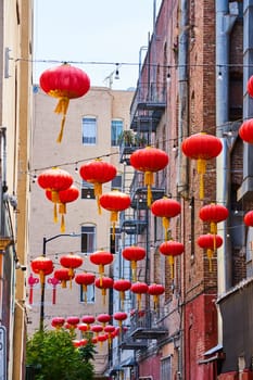 Image of Red Chinese paper lanterns hanging from wires attached to buildings and fire escapes