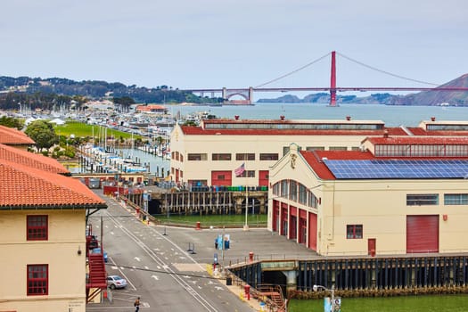 Image of Warehouses on piers with empty street and distant boat docks leading to Golden Gate Bridge