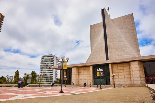 Image of People walking on sidewalk entrance of Cathedral of Saint Mary of the Assumption on cloudy day