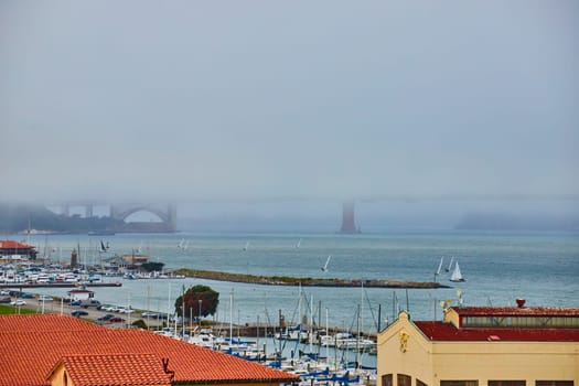 Image of Foggy view of San Francisco Bay with boats and distant obscured Golden Gate Bridge