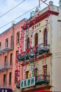 Image of Fire escape covered in string of American and Chinese flags on white brick building