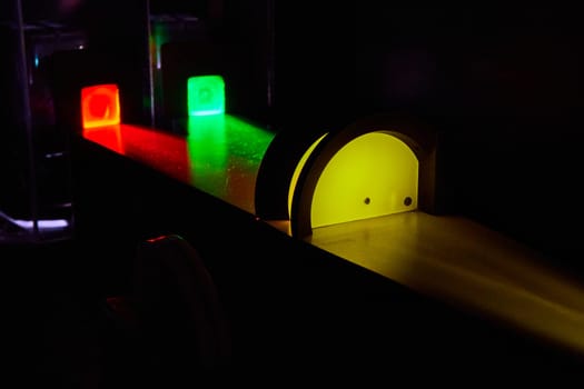 Image of Green and red light combine into yellow beam in black room science experiment