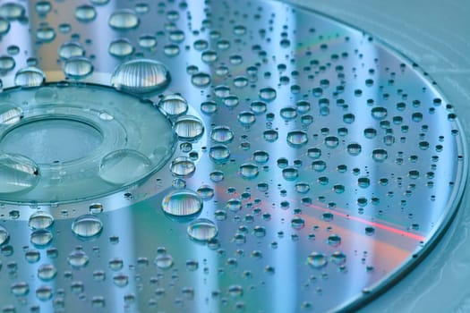 Image of Calm blue and silver surface with silvery water droplets on CD surface and slate blue background