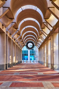 Image of Symmetrical tunnel ceiling with black circular opening at the end and brick floor