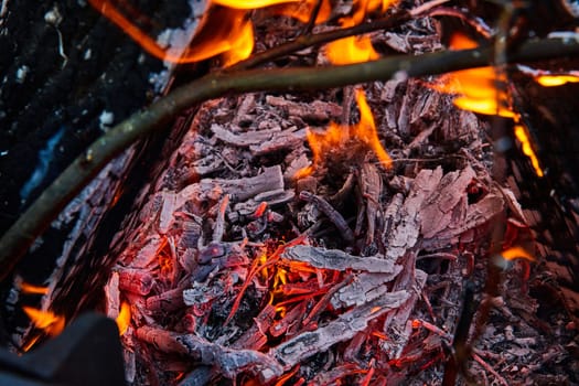 Image of Close up of embers burning with white ashes in a pile and yellow and orange flames