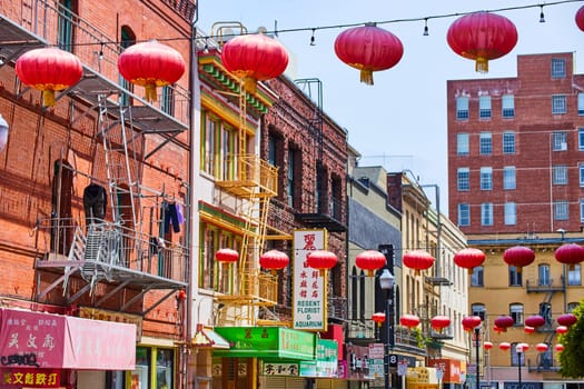 Image of Straight rows of red Chinese paper lanterns with shop and restaurant signs