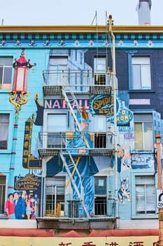 Image of Large art mural on side of blue building with Shanghai Low and a variety of people and a dog