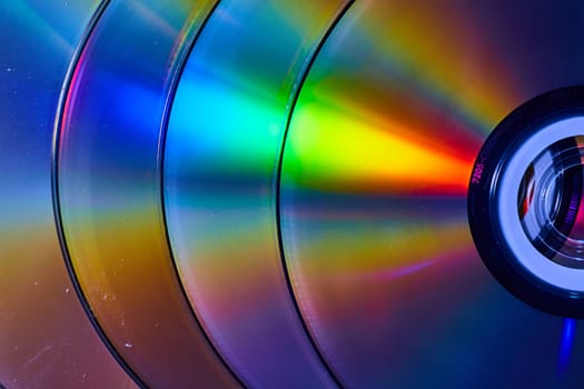 Image of Abstract stack of four silvery CDs with reflective rainbow bursts of light on surface