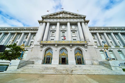 Image of San Francisco gilded city hall entrance with fancy light posts and American flag