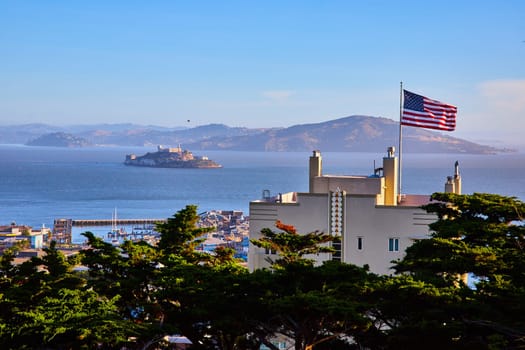 Image of Open American Flag flapping in wind on building looking out at Alcatraz Island near evening
