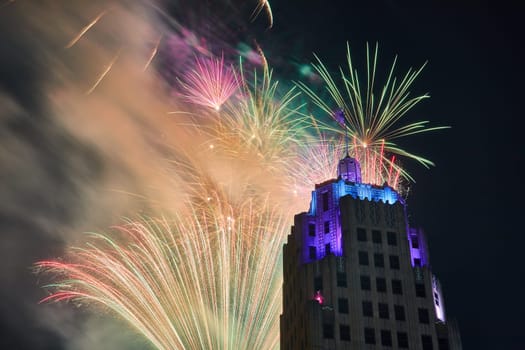 Image of Zoomed in view of dazzling fireworks behind Lincoln Tower with purple and blue lights in Fort Wayne