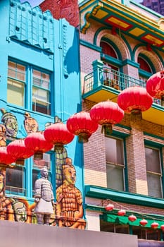 Image of Statue of Chinese man standing in front of colorful soldier mural with red lanterns