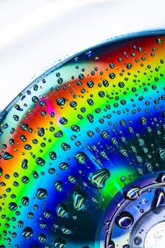 Image of Abstract close up of CD with rainbow colors on metallic surface with bubbles