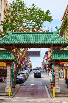 Image of Chinatown entrance with golden dragons and green fish roof with tree behind it in San Francisco