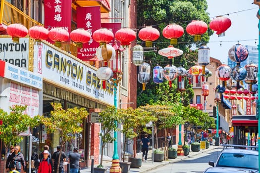 Image of Busy street in Chinatown with colorful hanging lanterns and shops with pedestrians and cars