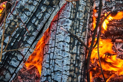 Image of Close up detailed view of two ashen logs with tiny orange and yellow flames