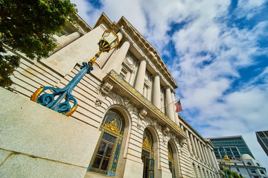 Image of Close up of blue and gold lamp post with American flag dangling in front of city hall entrance