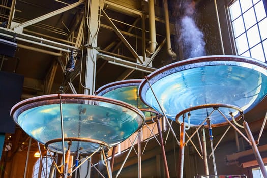 Image of Giant vats of water in clear bowls on long copper stands with one steaming and spitting water