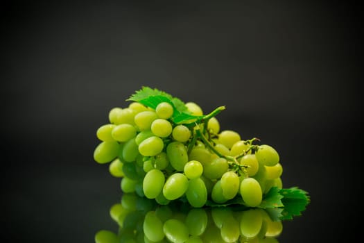 A bunch of ripe green grapes with leaves, isolated on a black background.
