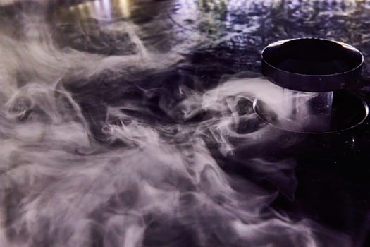 Image of White misty fog swirling around with cloud maker in black container