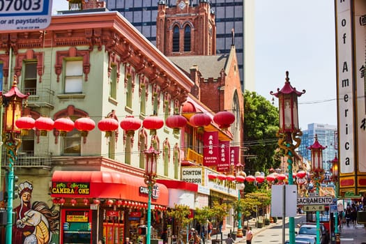 Image of Chinatown street with mural of man riding dragon and shops with red lanterns hanging overhead