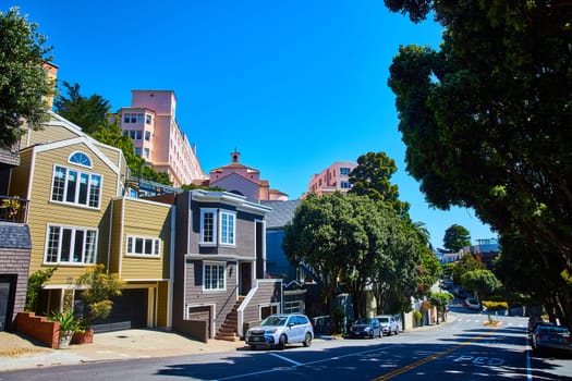 Image of Colorful yellow and gray houses with cars on street and pink colored housing above